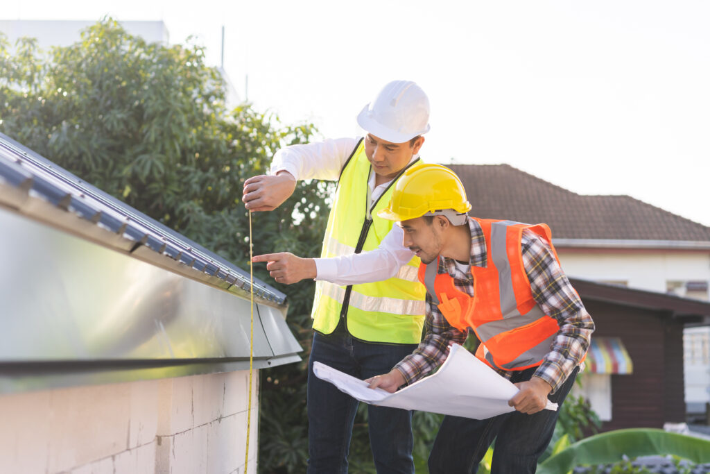 how to measure a roof for metal roofing Builder team, foreman house asian young engineer, architect, contractor discussing metal sheet rooftop on blueprint follow project to build industrial plan at outdoor site. Engineering worker people.